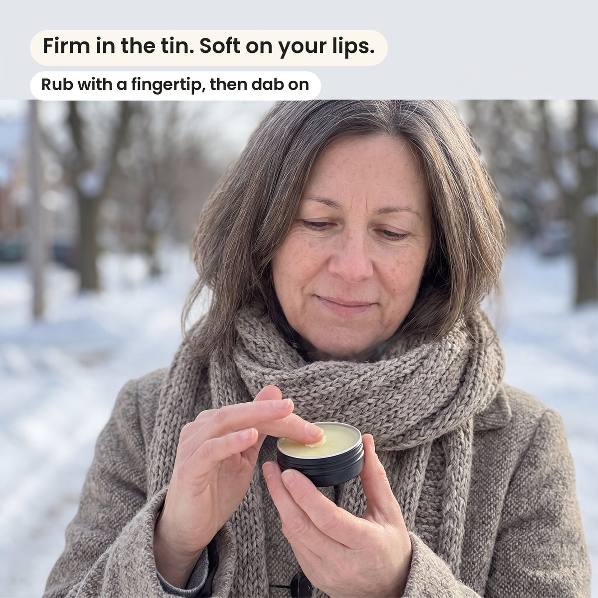 A woman on a winter day touching the balm in an open tin